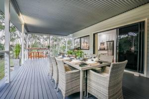 - une table à manger et des chaises sur une terrasse couverte dans l'établissement Agnes Bliss - Stunning four-bedroom beach house, à Agnes Water