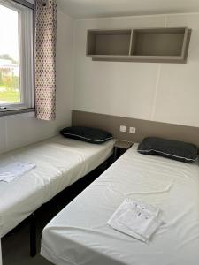 two beds in a room with a window at Mobilhome Ck171 Siblu Les Charmettes in Les Mathes