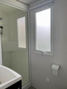 een witte badkamer met een raam en een wastafel bij Mobilhome Ck171 Siblu Les Charmettes in Les Mathes