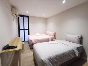 a room with two beds and a table and a desk at Autumn Guesthouse's near Jalan Alor Bukit Bintang in Kuala Lumpur