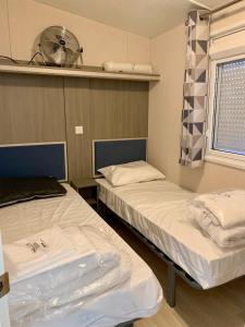 two beds in a hospital room with a fan at Mobile home Cc780 Siblu Les Charmettes close to the sea in Les Mathes