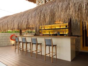 a bar with chairs and a counter with a straw roof at IZE Canggu by LifestyleRetreats in Canggu