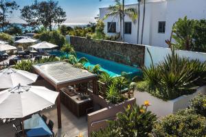 um pátio exterior com mesas e guarda-sóis e uma piscina em Bayview Beachfront Apartments, in town right on the beach em Byron Bay