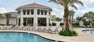 uma casa com piscina e cadeiras e uma palmeira em 4810 LL - 5BD Private Pool Townhome - Storey Lake em Kissimmee