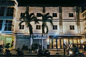 two palm trees in front of a building at night at Belladama Hotel in San Carlos