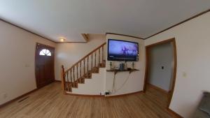 a living room with a staircase with a flat screen tv at River Dream Lake Murray Getaway in Saluda