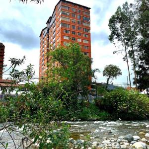 ein großes Backsteingebäude neben einem Fluss mit Bäumen in der Unterkunft Urban Andes Retreat in Cuenca