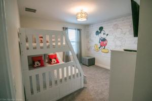 a childs bedroom with a white crib and mickey mouse wallpaper at 1581 PD - Exquisite 6BR Haven: Private Pool in Davenport