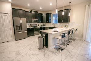 a kitchen with black cabinets and a white floor at 1581 PD - Exquisite 6BR Haven: Private Pool in Davenport +27 photos