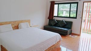 Un dormitorio con una cama y una silla de cuero negro en บ้านชมดาวรีสอร์ทบึงโขงหลง en Ban Don Klang