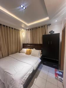 1 dormitorio con 1 cama y TV de pantalla plana en Luxury 2 Bedroom Apartment in the Heart of WUSE 2, WIFI,NETFLIX, 24hrs Light en Abuja