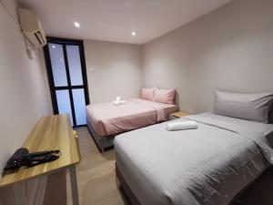 a room with two beds and a table with a desk at Autumn Guesthouse's near Jalan Alor Bukit Bintang in Kuala Lumpur