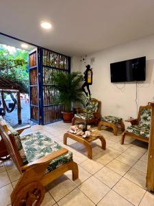 uma sala de estar com cadeiras e uma televisão de ecrã plano em Hostel Beach House em Rincón