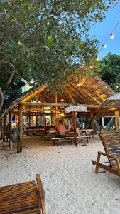 een houten paviljoen op een zandstrand met banken en bomen bij Hostel Beach House in Rincón