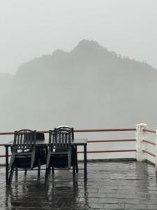 two chairs and a table on a pier in the rain at Club ES Deurali Resort in Pokhara