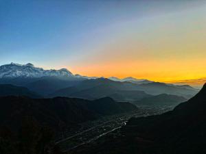 Blick auf ein Tal bei Sonnenuntergang mit Bergen in der Unterkunft Club ES Deurali Resort in Pokhara