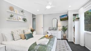 a white bedroom with a white bed and a window at Natures Nest on Nari in Moss Vale
