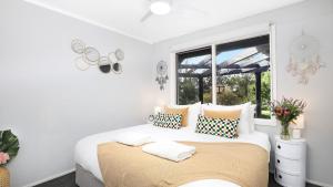 a white bedroom with a bed and a window at Natures Nest on Nari in Moss Vale