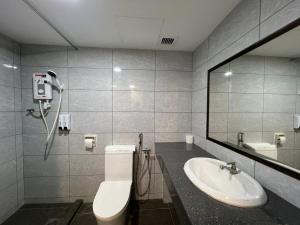 een badkamer met een wastafel, een toilet en een spiegel bij Remington Hotel in Muar