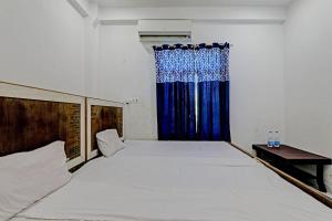a bedroom with a large bed with a blue curtain at OYO ONCE MORE RESTAURANT AND CAFE in Lukerganj