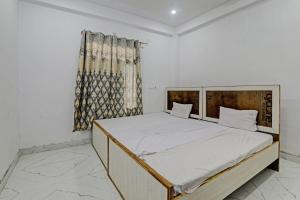 um quarto com uma cama grande com lençóis brancos e uma janela em OYO ONCE MORE RESTAURANT AND CAFE em Lukerganj
