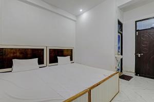 a bedroom with a large white bed with a wooden headboard at OYO ONCE MORE RESTAURANT AND CAFE in Lukerganj