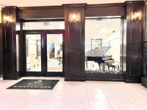 a grand piano in a lobby with glass doors at Hotel Caesars in Tijuana