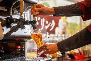 una persona está vertiendo un vaso de cerveza en Kami no yama Azumaya, en Kaminoyama