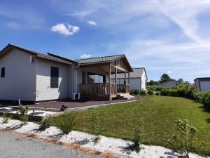 a white house with a porch and a yard at Chalet confort 3 chambres, piscine chauffée, entre mer et nature près du Golfe du Morbihan - FR-1-783-3 in Marzan