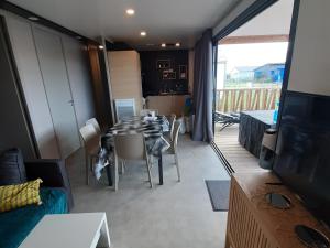 a living room with a table and chairs and a television at Chalet confort 3 chambres, piscine chauffée, entre mer et nature près du Golfe du Morbihan - FR-1-783-3 in Marzan