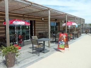 ein Restaurant mit Tischen und Sonnenschirmen auf einer Terrasse in der Unterkunft Chalet familial au calme avec piscine près du lac du Jaunay, proche plages et activités. - FR-1-783-21 in La Chapelle-Hermier + 7 Fotos