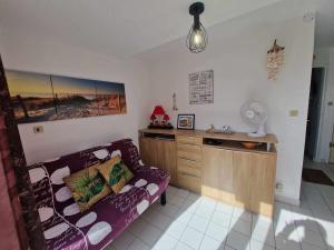 ein Wohnzimmer mit einem lila Sofa und einem Schreibtisch in der Unterkunft Appartement Marseillan-Plage, 2 pièces, 4 personnes - FR-1-326-815 in Marseillan
