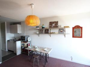 a kitchen with a table and a small kitchen with a refrigerator at Studio Chamrousse, 1 pièce, 4 personnes - FR-1-549-138 in Chamrousse