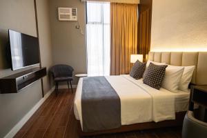 um quarto de hotel com uma cama e uma televisão em Amber Hotel - Cebu em Cebu
