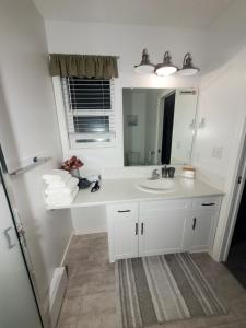 Baño blanco con lavabo y espejo en K E vacation house, en Nanaimo