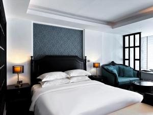 - une chambre avec un lit blanc et une chaise bleue dans l'établissement Glory Boutique Suites 清迈古城荣耀精品酒店, à Chiang Mai