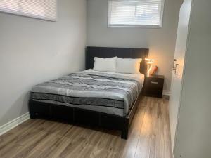 a bedroom with a bed with a wooden floor and two windows at A bedroom in a basement in Guelph