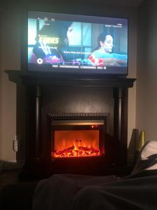 un televisor sobre una chimenea con fuego. en A bedroom in a basement en Guelph