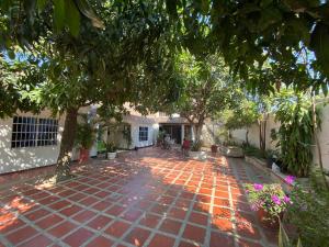 a garden with a brick patio with trees and flowers at Casa Vecina Hostal in Santa Marta