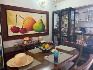 a dining room with a table and a painting of fruit at Casa Vecina Hostal in Santa Marta +26 photos