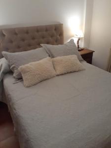 ein Bett mit weißen Laken und Kissen darauf in der Unterkunft Terrazas del Sur in San Carlos de Bariloche