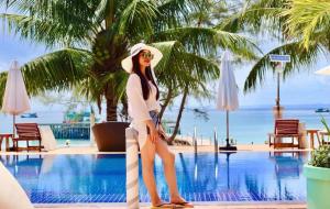 a woman in a hat standing next to a swimming pool at May Beach Resort in Koh Rong Island