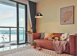 a living room with a brown couch and a large window at Yussy Homestay at R&F Princess Cove in Johor Bahru +108 photos