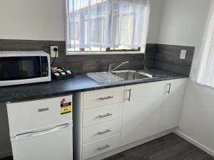 a kitchen with a sink and a microwave at Magnolia Court Motel in Opotiki
