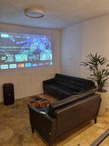 un soggiorno con divano nero e grande schermo di Casa do Descanso com jacuzzi em Igaratá a Igaratá