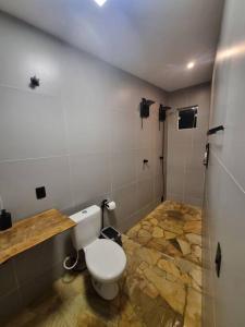 La salle de bains est pourvue de toilettes et d'un sol en pierre. dans l'établissement Casa do Descanso com jacuzzi em Igaratá, à Igaratá
