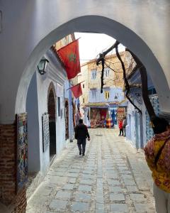a man walking down a street under an archway at Tranquil Oasis in Chefchaouen in Chefchaouene