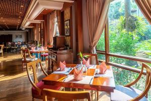 restauracja ze stołami i krzesłami oraz dużym oknem w obiekcie Sokha Angkor Resort w Siem Reap