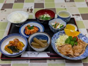 Kawabata Ryokan Takehara by Tabist في Takekara: صينية مع أطباق من الطعام على طاولة