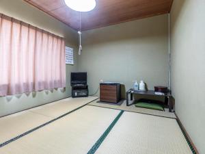 ein Wohnzimmer mit einem Tisch und einem TV in der Unterkunft Kawabata Ryokan Takehara by Tabist in Takehara